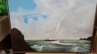 Full view of the oil painting depicting a sailboat on the ocean with rocky outcrops and cloudy sky, showing the overall artwork and frame.
