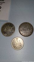 Photo showing the full view of the two Canadian silver dollars from 1962 and 1965, and the 1966 50 cent piece with the Canadian coat of arms.