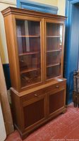 Full front view of the walnut china cabinet showing glass doors, shelves, drawer, and lower cabinet doors.