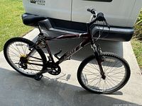 Full side view of the maroon and white 18-speed men's mountain bike parked outside on pavement.