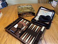 Trivial Pursuit Star Wars Classic Trilogy Collector's Edition game box beside a leather backgammon set with checkers and dice on a wooden table