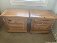 Pair of Broyhill wooden bedside tables with two drawers each, shown side by side against wall under window