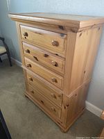 Photo showing front and side view of wooden tall dresser with four drawers and wooden knob handles.