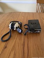 Photo showing Panasonic CB radio, headset, and microphone arranged on wooden table, viewed from above.