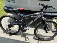 Side view of Schwinn S25 mountain bike leaning against a white van, showing tires, frame, seat and handlebars.