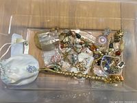 Top-down view showing assorted women's costume jewelry pieces including necklaces, bracelets, earrings, and a small white pouch.