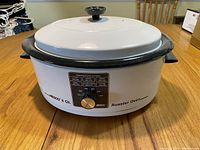 Front view of white Nesco 6 Qt roaster oven with black trim, lid on, control dial visible