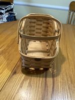 Full view of rectangular wooden woven basket with two handles and open top.