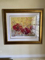 Front view of the framed abstract floral painting with red flowers and gold accents hung on a wall.