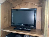 LG 26-inch television on wooden shelf with remote control in front