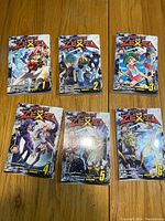 Photo of all six Yu-Gi-Oh! ZEXAL manga volumes from 1 to 6, arranged on a wooden floor, showing front covers with colorful manga artwork and numbering.