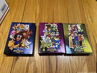 Three Digimon DVD volumes 1 to 3 displayed side by side on wooden surface, showing colorful character art on the front covers.