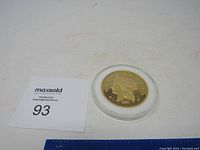 Replica gold coin in round clear protective case placed on white background with lot number card.