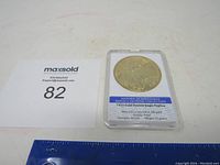 Photo of the 1933 Gold Double Eagle replica coin in its protective plastic case along with a ruler and lot number card for scale.