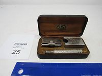 Antique Gem razor set inside its vintage fitted case showing the razor, blade holder, and blade case aligned inside a velvet-lined interior with GEM brand logo.