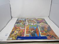 Top down photo of six comic books arranged in two rows, three Ironman books on top, three Hawkman books on bottom, with a ruler for scale.
