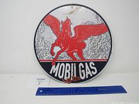Front view of Mobil Gas round metal sign showing red Pegasus with wings, 'MOBIL GAS' text, minor rust bottom center