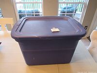 View of the dark blue plastic tote with lid from front, showing overall condition and lid fit.