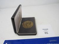 Photo shows the coin in the open black display case with satin interior lining.