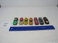 Front view of seven NASCAR diecast cars lined up side by side with a ruler indicating length and auction lot tag visible