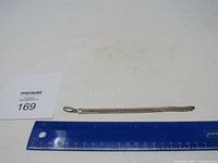Full length view of sterling silver bracelet with ruler for scale, showing approximately 7.5 inches length and lobster clasp.