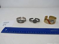 Overview of all three bangle-style watches laid out with ruler for scale.