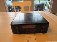 Black rectangular metal carrying case with two twist-lock clasps on the front and a metal identification plate.