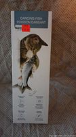 Box of cat toy Dancing Fish featuring cat playing with the toy fish, showing box front with product name and image.