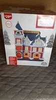 Photo of the box showing the front of the Holiday Time Fire Station ceramic Christmas decoration with light-up feature, price tag visible.