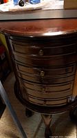 Front view of the wooden jewelry stand showing multiple drawers with brass knobs and carved legs.