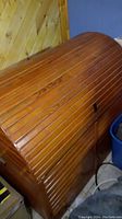 Front and angled view of the large wooden chest showing horizontal wood slats and curved dome top.