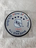 Top view of the hockey puck showing the NHL logo and commemorative text about the 1947 Toronto All-Star Game.