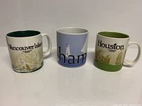 Three Starbucks collectible mugs featuring Vancouver Island, Houston, and Bahamas designs arranged in a row