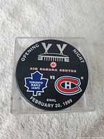 Front face of the black NHL commemorative puck displaying Air Canada Centre opening night details and team logos.