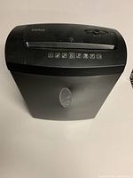 Front angle view of a black Staples paper shredder showing top controls, paper slot and safety icons on the front.