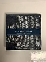 Front of the packaging showing Tommy Hilfiger branding and the hat and scarf inside the box with a navy blue and white knit pattern.