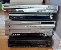 Front view of five stacked electronic units including Panasonic, RCA, Toshiba, LG DVD players and a JVC VCR.
