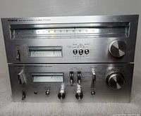 Front views of stacked amplifier and tuner showing silver faceplates, analog meters, knobs and switches