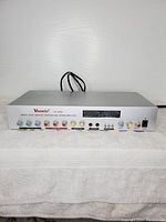 Front view of Vsonic K88A amplifier showing control knobs, input and output ports, power switch, and digital display area. Casing is silver metal.