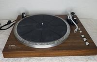 Front angle of Yamaha YP-D3 turntable showing wood base, rubber mat on platter, tone arm, and control knobs.