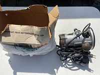 Cardboard box in worn condition, includes plastic bag insert, partially open showing some wear and text.