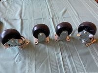 Four castor wheels laid out on a fabric surface, showing two swivel wheels with locking levers and two fixed wheels.