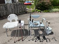 Wide view of entire lot showing all items including canes, commode chair with bucket, tub/shower bench, and bed tray