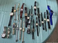 Full view of all 22 assorted wristwatches showing variety in styles, colors and band materials.