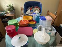 Assorted used Tupperware containers and lids on table with chairs and plants in background