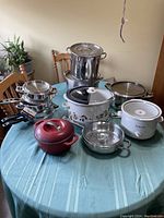 Wide view of the entire lot spread on a table with multiple pots and crockpots visible.