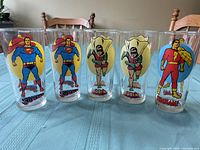 Front view of 5 glasses showing colorful DC Comics superheroes Superman, Robin, and Shazam.