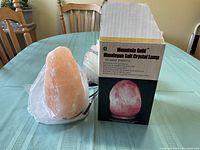 Himalayan salt crystal lamp sitting on table next to original Mountain Gold box with product info and image.