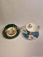 Two fine bone china teacup and saucer sets displayed side by side on a plain background, showing the contrasting colors and gold accents.