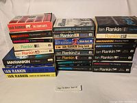 Full view of the Ian Rankin book lot showing multiple stacked paperback and hardcover editions arranged in three stacks.